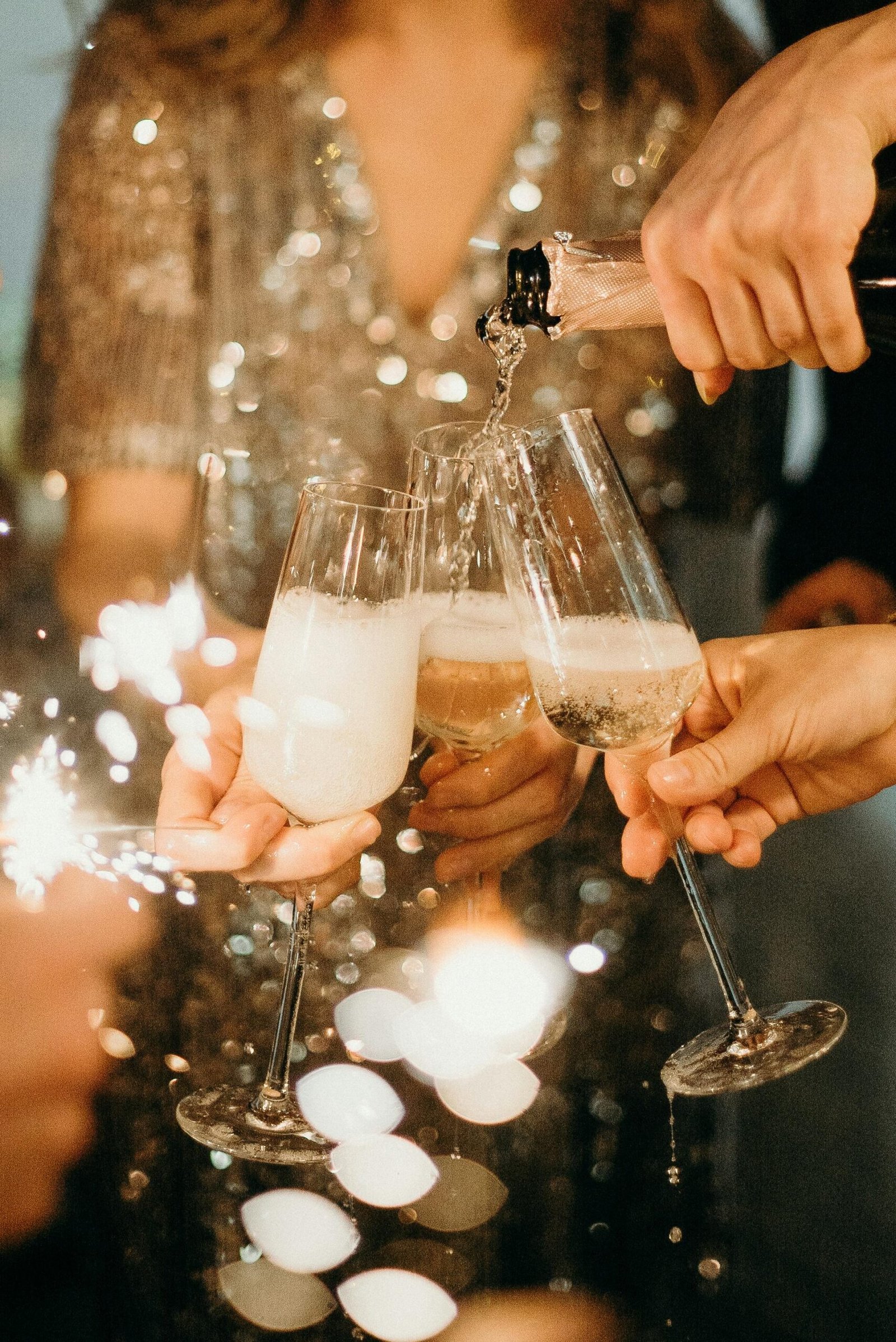 People toasting with champagne glasses amidst sparklers at a festive party.